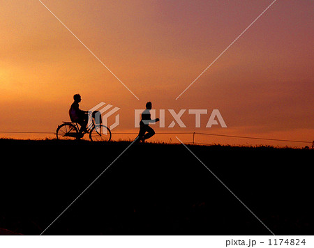 夕焼け 自転車 ジョギング 土手の写真素材