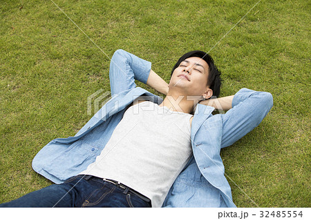 男性 寝転ぶ 仰向け 芝生の写真素材