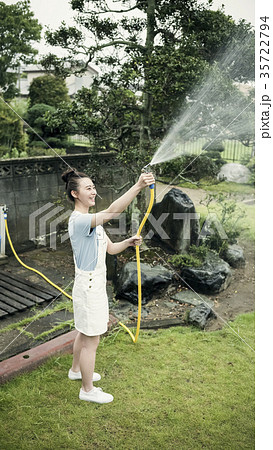 女性 庭 ホース 水やりの写真素材