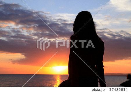 女の子 海 後ろ姿 夕暮れの写真素材