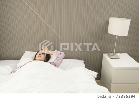 病気で寝込んでいる女性/体調の悪い女性/ベットに寝ている美しい女性