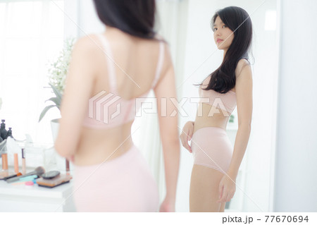 Beautiful young asian woman in underwear looking in mirror with