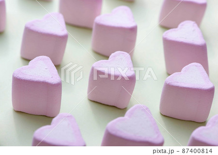 Waffle cone with heart-shaped marshmallows, close-up on a blue