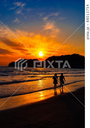 海 夕焼け 女の子 波打ち際の写真素材