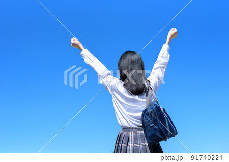 青空 女性 ガッツポーズ 後姿の写真素材