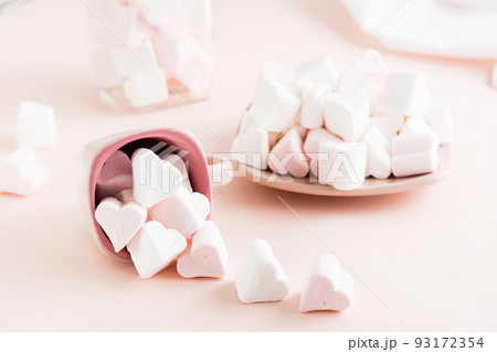 A cup with heart-shaped marshmallows, close-up on a blue wooden