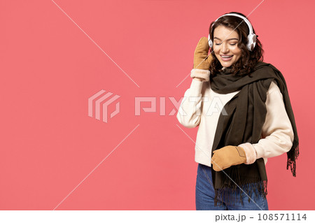 Smiling blonde woman in winter clothes hands near face in snowy