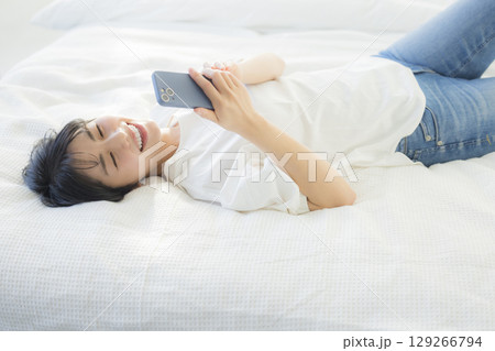 ベッドでスマホを見る女性の写真素材 [129266794] - PIXTA